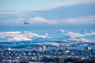 Uçak bir Reykjavik şehir merkezinde bir altın akşam ışık altında iniyor. Sermaye şehir İzlanda Reykjavik kış karla kaplı dağlarla çevrili.