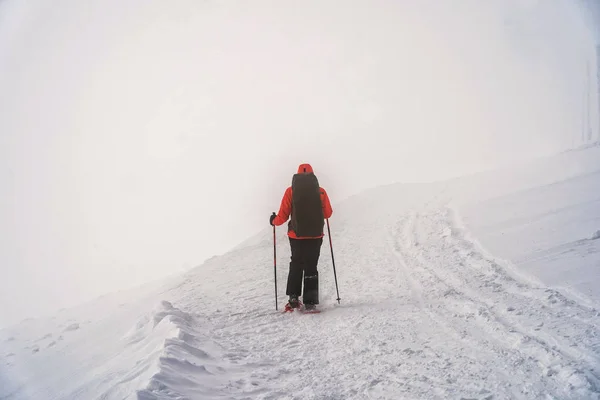 Winter sport activity. Woman hiker hiking with backpack and snow — ストック写真