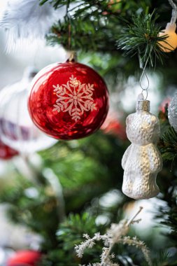 Noel arkaplanı. Yeşil bir Noel ağacında asılı kırmızı ve gümüş mücevherlerin ve şenlikli süslemelerin detaylı görüntüsü.