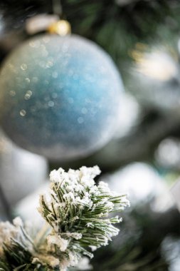 Noel arkaplanı. Beyaz bir Noel ağacında asılı mavi ve gümüş mücevherlerin ve şenlikli süslemelerin detaylı görüntüsü.