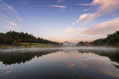 Huzurlu dağ manzarası sakin göl, renkli ağaçlar ve altın sıcacık bir ışıkta yüksek zirveler. Slovakya 'daki Yüksek Tatras Ulusal Parkı manzarası.