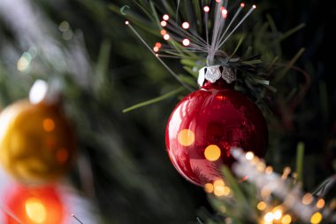 Noel arkaplanı. Yeşil bir Noel ağacında asılı kırmızı ve gümüş mücevherlerin ve şenlikli süslemelerin detaylı görüntüsü.