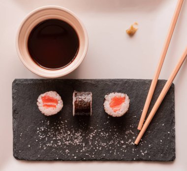 Soya sosu ve çubuklarla süslenmiş kare bir tabakta suşi.
