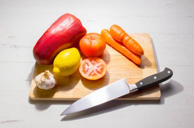 Biber, limon, havuç, domates ve sarımsak. Bıçakla, tahta tahtada, beyaz ahşap masada.