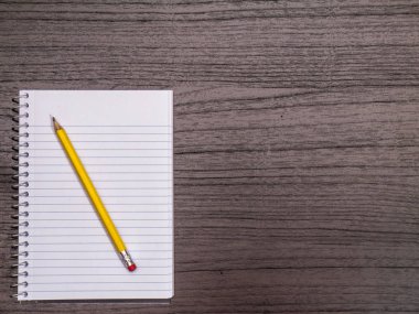 Koyu ahşap masaüstü, Spiral defter, kalem 