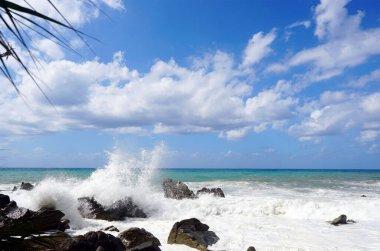 Deniz dalgaları kayalara çarpıp su damlacıkları yağmuru yaratıyor.