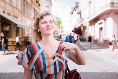 Yüzünde gülümseme olan bir kız. Mutluluğun ifadesi. Seyahat, rahatlama. Şehirde dolaşıyorum..