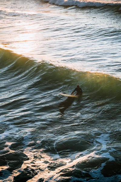 Hombre adulto sentado en una tabla larga durante la puesta del sol — Foto de Stock