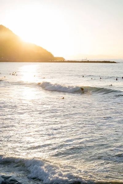 Surfeurs chevauchant les vagues sur Zurriola Beach à San Sebastian pendant le coucher du soleil — Photo