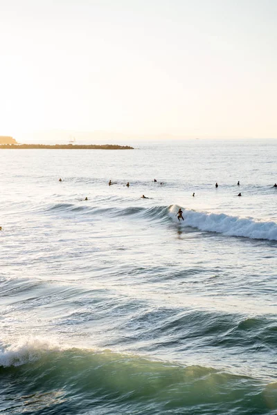 Surfaři jezdící na vlnách na pláži Zurriola v San Sebastiánu během západu slunce — Stock fotografie