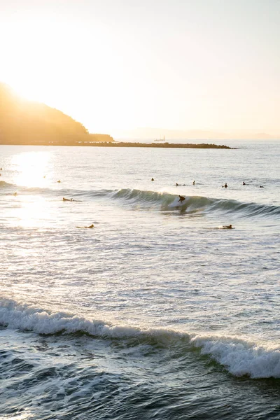 Surfeurs chevauchant les vagues sur Zurriola Beach à San Sebastian pendant le coucher du soleil — Photo