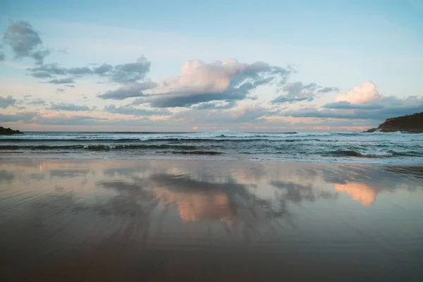 Las nubes de color pastel paleta en el cielo reflejadas en la costa durante la marea baja. — Foto de Stock