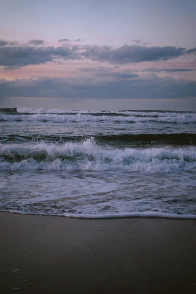 Las olas que rompen durante la marea baja en la playa de Zurriola después de la puesta del sol. — Foto de Stock