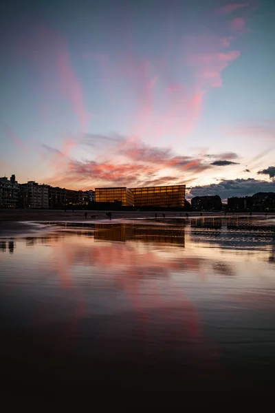 Nubes de color rosa en el cielo de San Sebastián después del atardecer reflejadas en la costa de la playa de Zurriola. — Foto de Stock