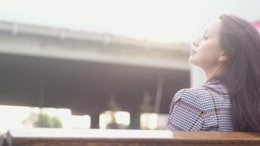 woman in casual clothes sitting on wooden bench. girl is holding fragrant coffee. Girl drinking hot coffee in morning on bench. business morning. Business woman on a bench with a Cup of coffee or tea.