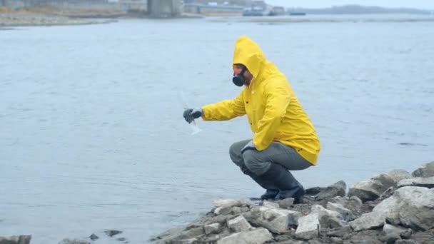 黄色のレインコートと呼吸マスクの生態学者は分析のために川から試験管に水を引き込みます きれいな惑星だ 世界を気にして 川からの水に関する研究です — ストック動画