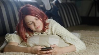 Kazaklı çekici bir kız evinde akıllı telefonuyla kanepede yatıyor. Telefon mesajı okuyan bir kadın. Haberleri ya da el hareketleriyle mesajları karıştırıyor. Modern aygıtlardaki fotoğraf ve videolara bak.