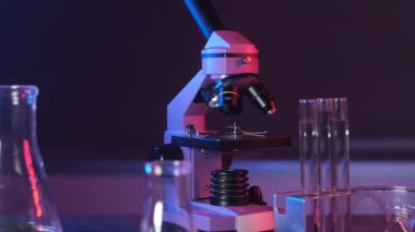 Bilimsel keşifler için laboratuvar ekipmanları. Laboratuvardaki cam tüplerin mikroskobu masada. Kimyasal biyolojik deneyler için laboratuarda panoramik çekim aletleri. Neon