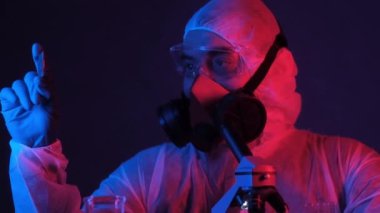 Maske ve eldiven takan beyaz tulumlu erkek mühendis bilgisayar işlemcisini neon ışıkta tutuyor. Biyometrikteki bilimsel ve endüstriyel gelişmeler. Ultra modern elektronik çip üretimi.