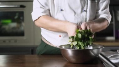 Aşçı taze maydanozu sudan çıkarır ve damlaları siler. Baharatları kağıt havluyla siler.