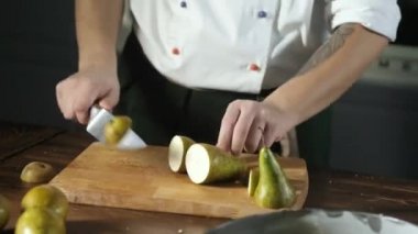 Baker olgun yeşil armutları keskin bir mutfak bıçağıyla keser. Bir adam tatlı turta ya da pasta yapmak için malzeme hazırlar. Fırında fırın. Lokanta mutfağında tatlı hazırlığı..