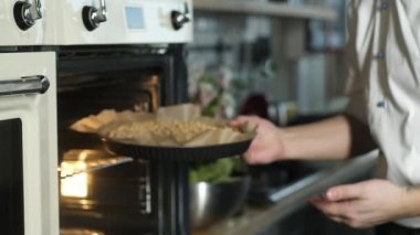 Fırında pişirme. Pasta şefi hamurla pişirme kabını fırına koyar. Mutfakta aletlerle kek pişirmek. Restoran mutfağı. Evde lezzetli bir turta pişirmek. Mutfaktaki şef gurme turtası yapıyor.