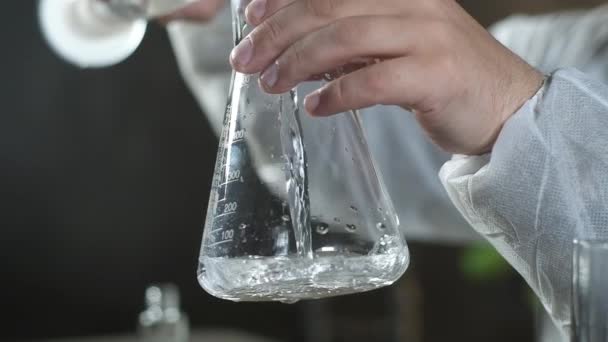 Wissenschaftler Chemielabor Gießt Klare Lösung Aus Dem Reagenzglas Ins Becherglas — Stockvideo
