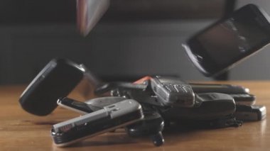 Eski modası geçmiş cep telefonuna yakın çekim. Modası geçmiş cep telefonları masaya düşüp kırılıyor. Eski çizilmiş, tozlu cep telefonları yığının içinde duruyor. Ofiste analog iletişim. Modern kablosuz teknoloji.