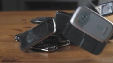 Eski modası geçmiş cep telefonuna yakın çekim. Modası geçmiş cep telefonları masaya düşüp kırılıyor. Eski çizilmiş, tozlu cep telefonları yığının içinde duruyor. Ofiste analog iletişim. Modern kablosuz teknoloji.