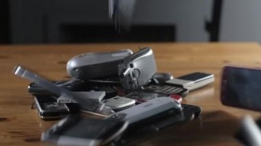 Modası geçmiş cep telefonları masaya düşüp kırılıyor. Eski çizilmiş, tozlu cep telefonları yığının içinde duruyor. Ofiste analog iletişim. Modern kablosuz teknoloji. Eski modası geçmiş cep telefonunun kapanışı