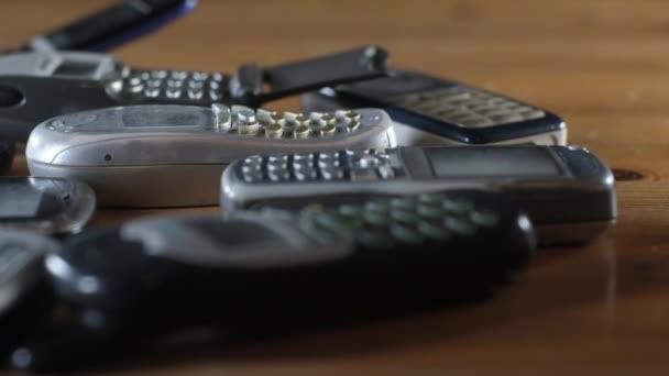 Los Viejos Teléfonos Celulares Rotos Rayados Polvorientos Yacen Apilados Sobre — Vídeo de stock