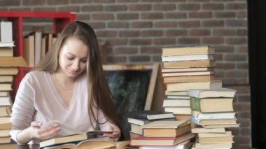 Sınav hazırlığı. Kadınlar bir sürü kitap arasında ders kitabı okurlar. Güzel bir genç kız evinde bir masada oturuyor ve sayfalarca kitap sayfalarını karıştırıyor. Öğrenciler evde okuyor. ev eğitimi.