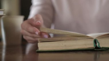 Kütüphanede büyük bir kitabın sayfalarını karıştıran bir öğrenci. Evde kitap okuyorum. Evde kendi kendini eğitme. Bir kız ders kitabı okuyor. Kapat..