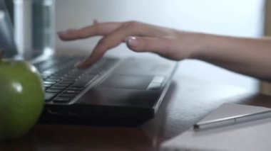 Ofiste dizüstü bilgisayarda çalışan güzel bir genç kız. Bir iş kadını bilgisayara metin yazdırır ve not defterine kalemle veri yazar..