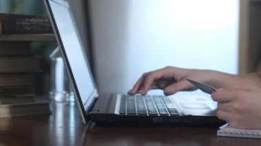 Kafkasyalı kız online alışveriş yapıyor. Güzel genç bir kadın bilgisayara kart verileri yazar. Kişi kredi kartı şifresini bilgisayara giriyor. mallar için internet üzerinden ödeme.