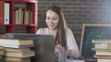 Güzel genç kız bir öğretmenle video bağlantısıyla konuşuyor. Mesafe öğrenme. Öğrenci sınavı internetten öğretmene geçer. Evde eğitim. Karantina sırasında evde çalışmak