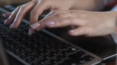 Bir kişi dizüstü bilgisayarda klavye kullanıyor. Bir kadın bilgisayarda yazı yazıyor. Büyük bir klanla.