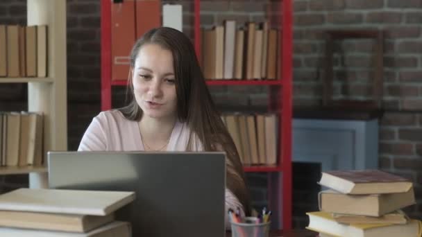 Καυκάσια Κοπέλα Κάθεται Στο Γραφείο Ανάμεσα Ένα Σωρό Βιβλία Και — Αρχείο Βίντεο