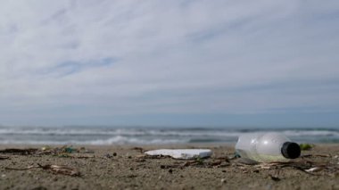 Plastik şişe deniz sahilinde. Bulanık dalgalı arka planı var. Gezegen 4K tasarruf ediyor.