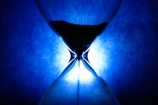 Ampulheta de cristal em fundo azul, conceito de passagem de tempo inspirador — Fotografia de Stock