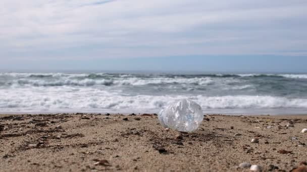 ぼやけた波の動きの背景の上のビーチでのプラスチックボトルのゴミ、惑星4k — ストック動画