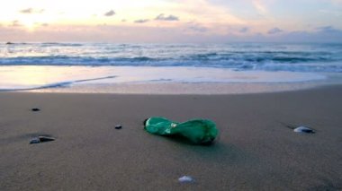 Young man pick up plastic bottle from sea shore on sunset time,pollution concept