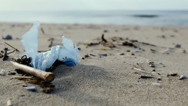 Botol plastik di pantai laut berangin dengan latar belakang gelombang biru, zoom out 4k — Stok Video