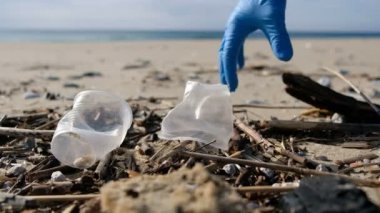 İnsanlar deniz kıyısında plastik cam çöpleri toplar, ekosistem kirliliğini temizler, 4k