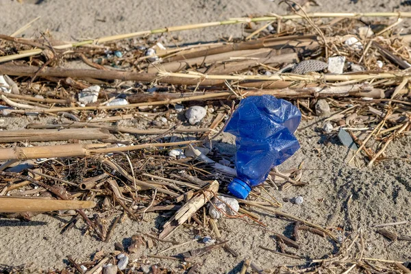 Blue Plastic bottle on polluted sea coast ecosystem after winter storm, cilento — Stock Photo, Image