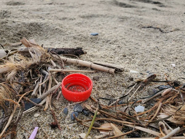 Garrafa de plástico vermelho cortiça na costa do mar arenoso, ecossistema poluído, microplásticos — Fotografia de Stock