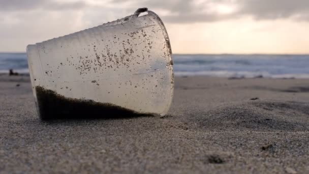 Vidrio plástico Basura en arena mar mar puesta del sol viento movimiento, naturaleza contaminada 4k — Vídeo de stock