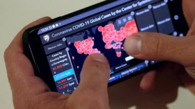Karantinadaki adam Coronavirus COVID-19 Global Case web sitesini akıllı telefondan kontrol ediyor.