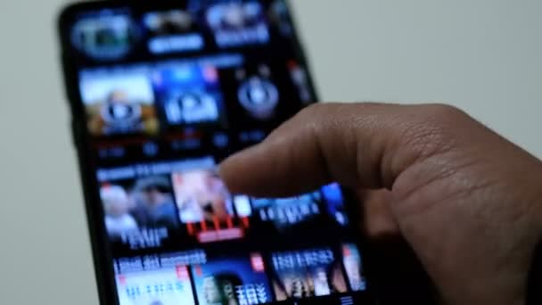 Man browsing on a smartphone netflix app series catalog, video streaming platform — стоковое видео