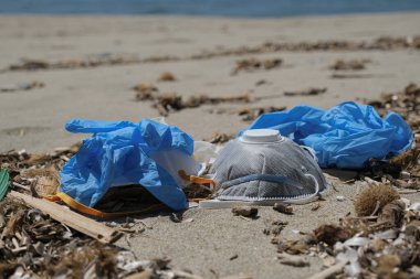 Ffp koruyucu virüs maskesi ve plastik eldivenler kumlu deniz kıyısında çöp, koronavirüs covid kirliliği hastalığı 